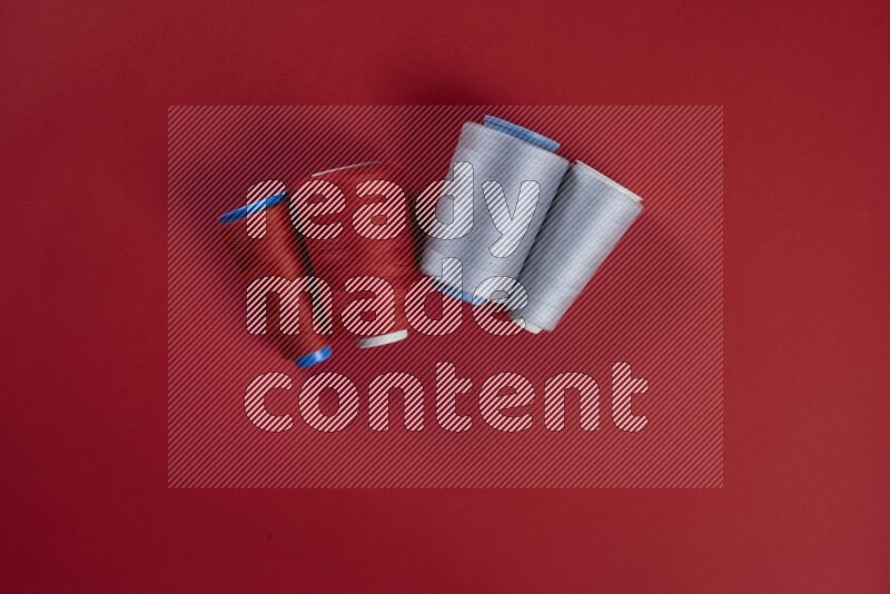 A grey collection of sewing and tailoring tools arranged on a red background