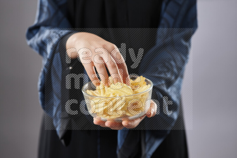 Woman in abaya holding different kinds of snacks in different positions