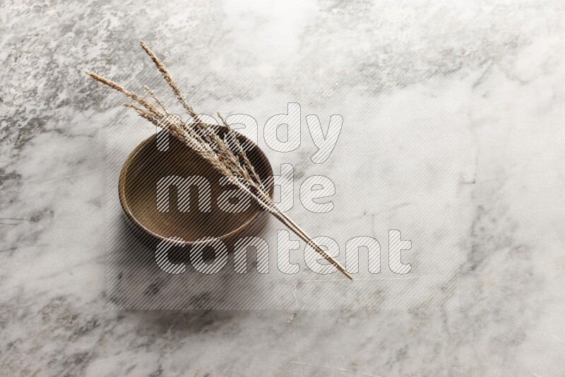 Wheat stalks on multicolored pottery oven plate on grey marble background