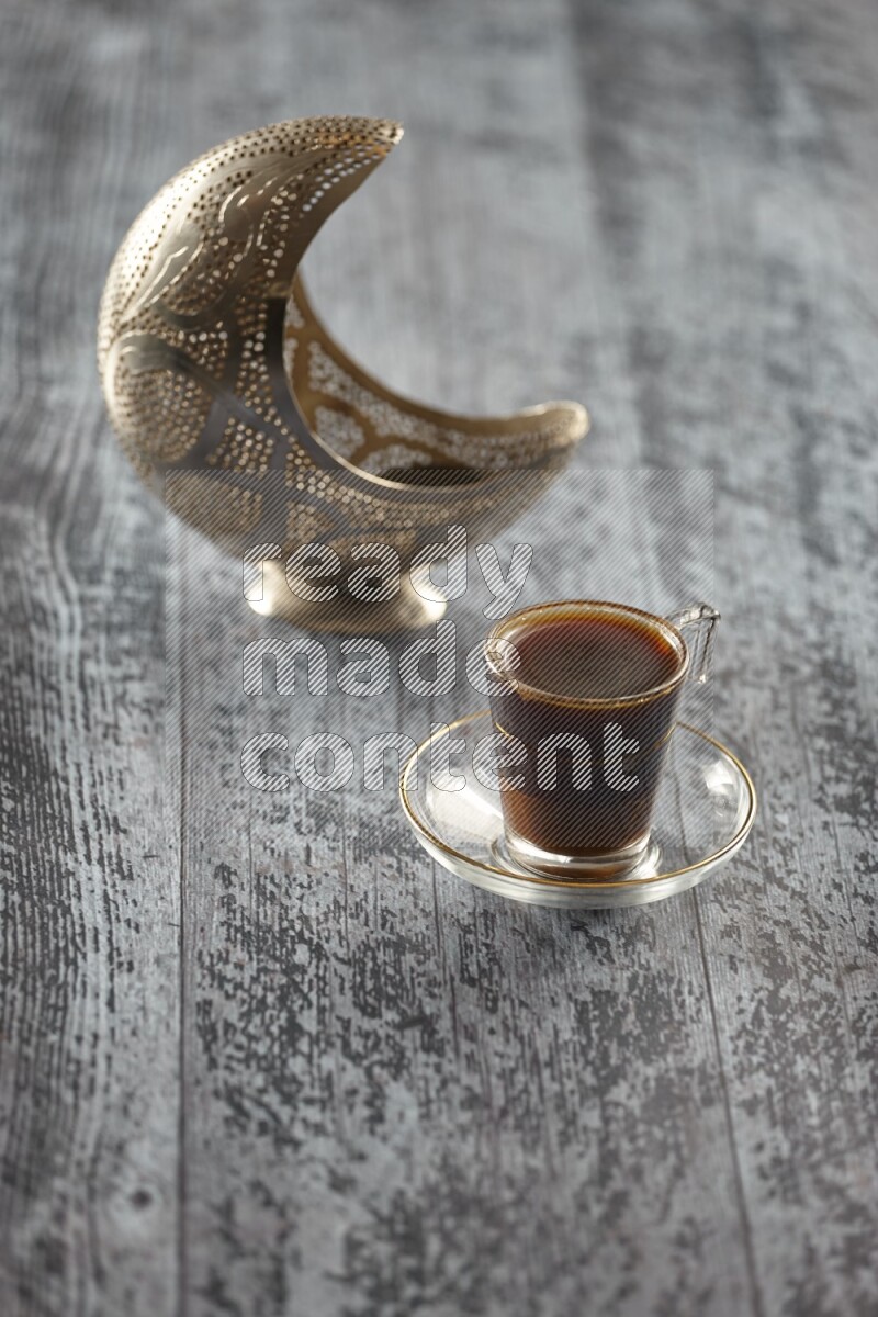 A silver lantern with different drinks, dates, nuts, prayer beads and quran on grey wooden background