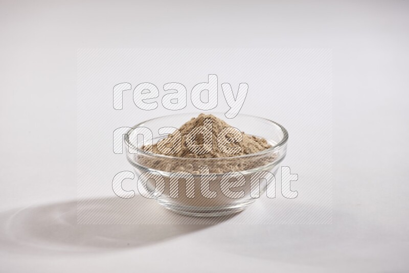 A glass bowl full of garlic powder on a white flooring