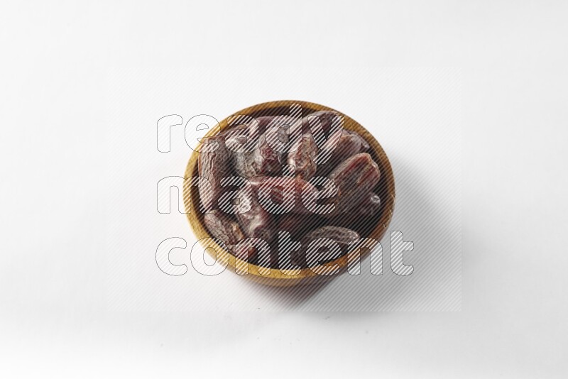 Dates in a wooden bowl on white background