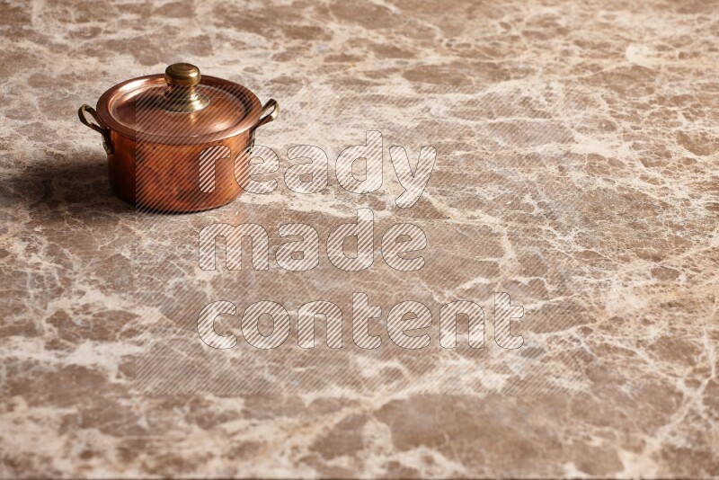 A small copper pot on beige marble background