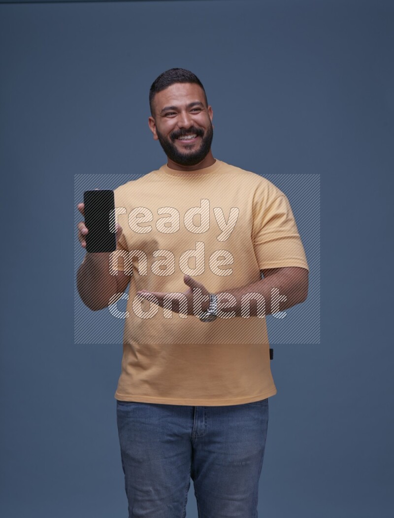 A man Showing His Smart Phone on Blue Background wearing Orange T-shirt