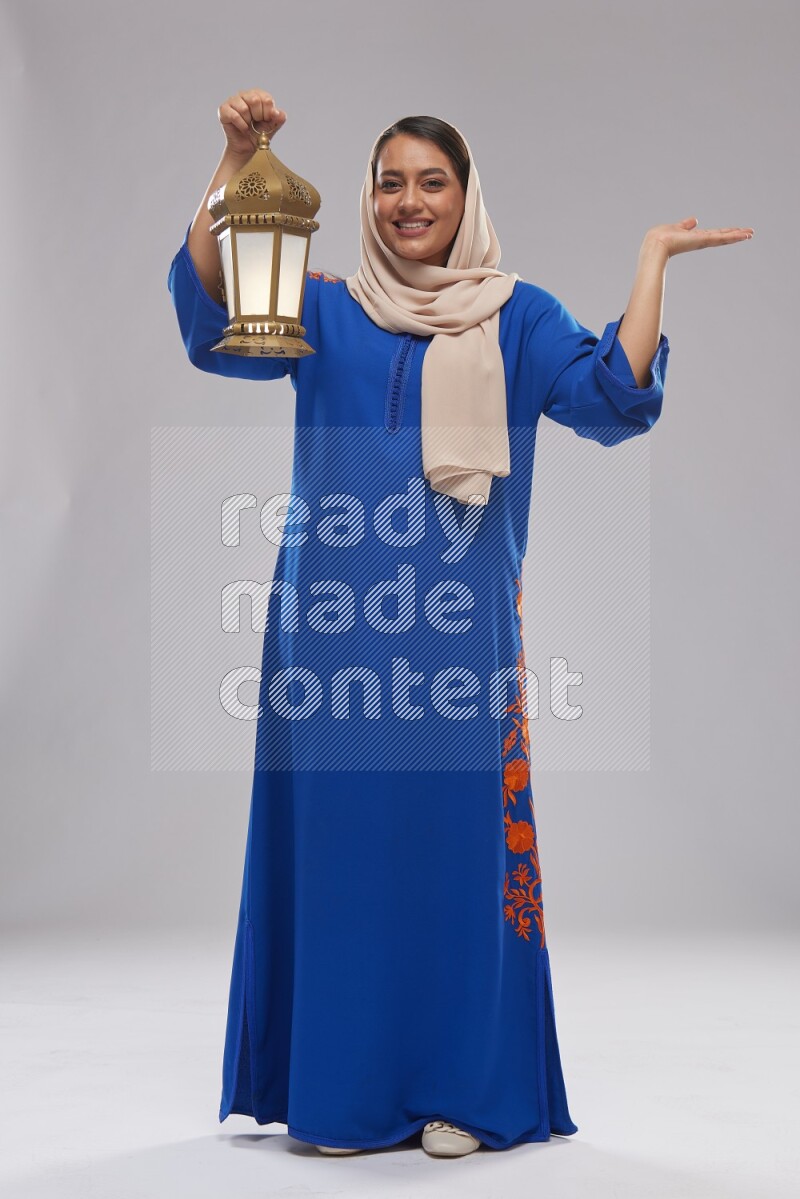 A Saudi woman standing wearing Jalabeya holding a lantern