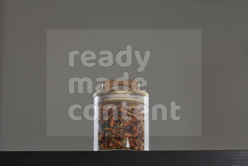 Chili pepper in a glass jar on black background
