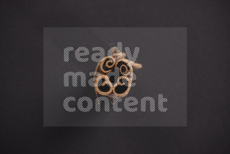 4 أعواد من القرفة مربوطة علي خلفية سوداء