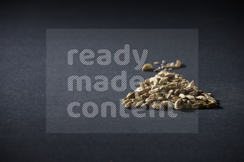 Cardamom in a triangle shape on black flooring
