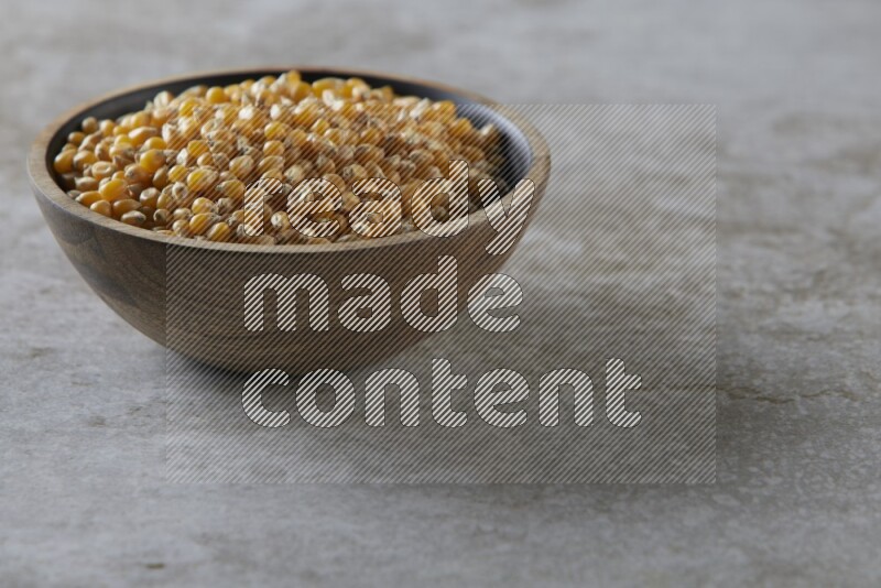 corn kernel in a wooden bowl on a grey textured countertop