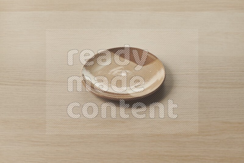 A multicolored pottery plate on light wooden background