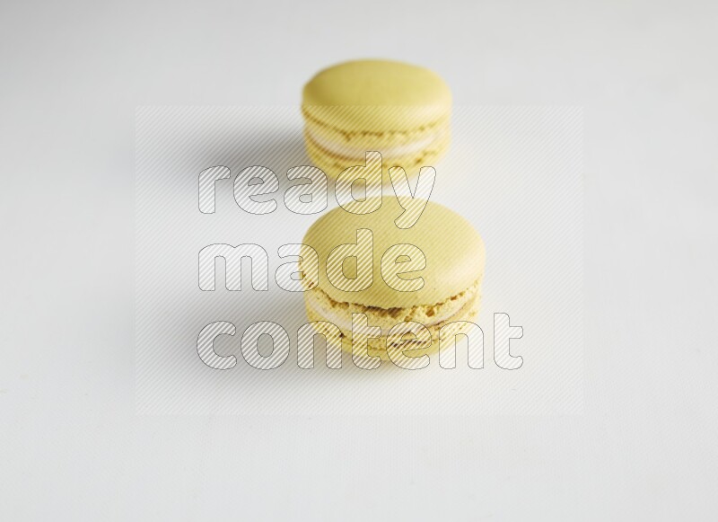 45º Shot of two Yellow Lime macarons on white background