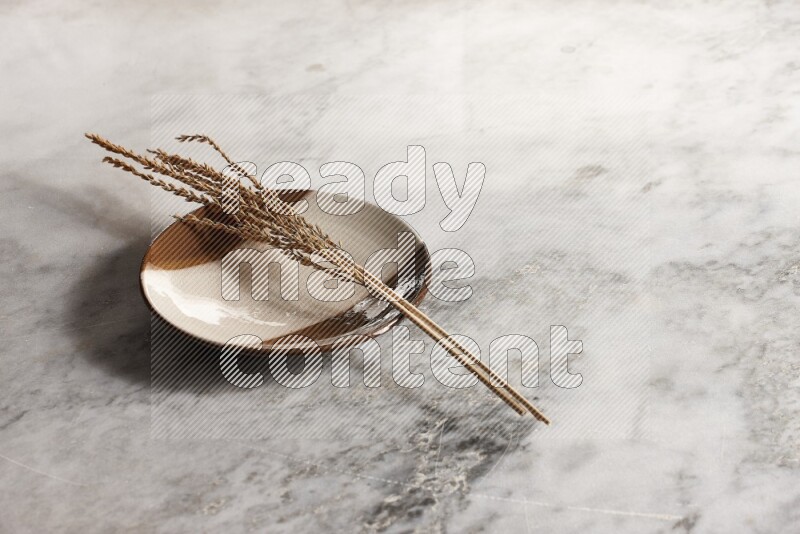 Wheat stalks on multicolored pottery plate on grey marble background