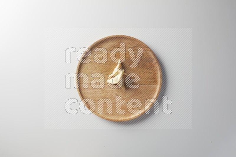 Two Sambosas on a wooden round plate on a white background