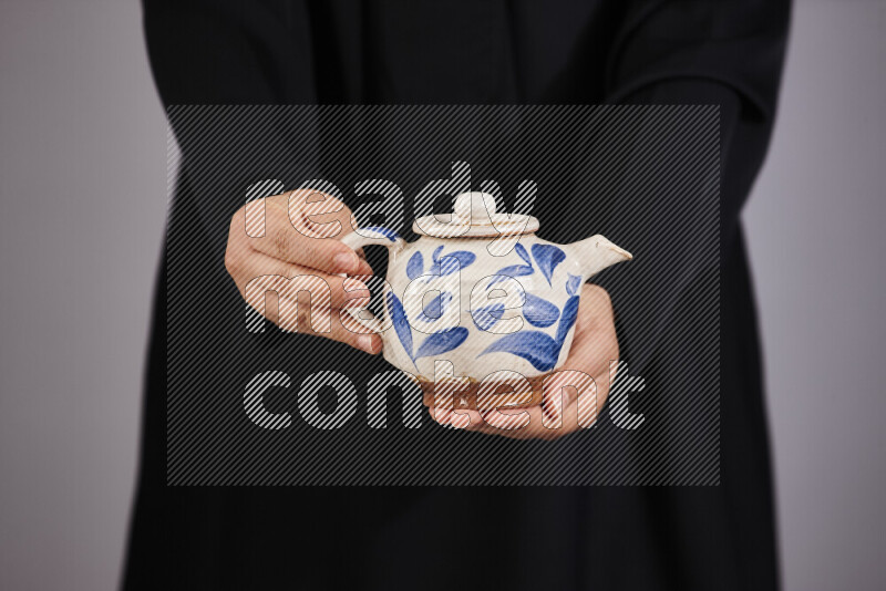 A woman in black abaya holding different pottery essentials in different positions
