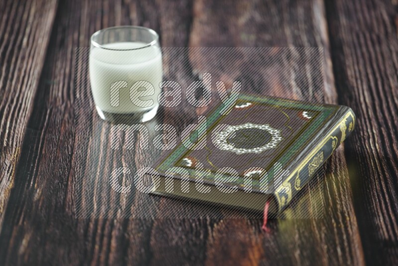 Quran with dates, prayer beads and different drinks all placed on wooden background