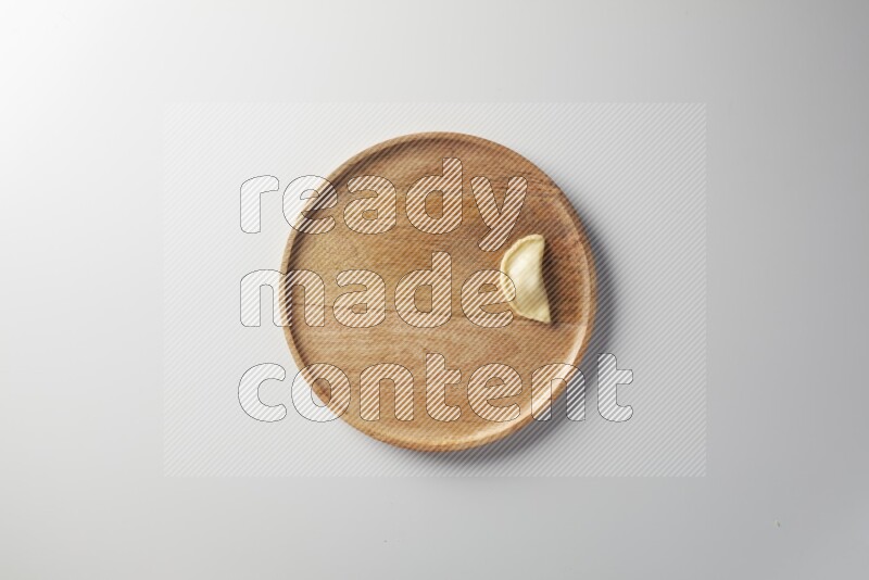 A single Sambosa on a wooden round plate on a white background