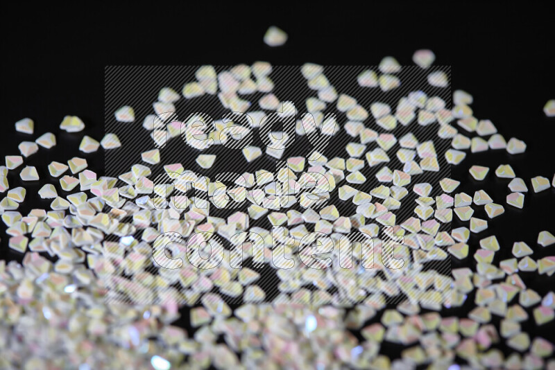 Colorful plastic shards for decoration scattered on a black background