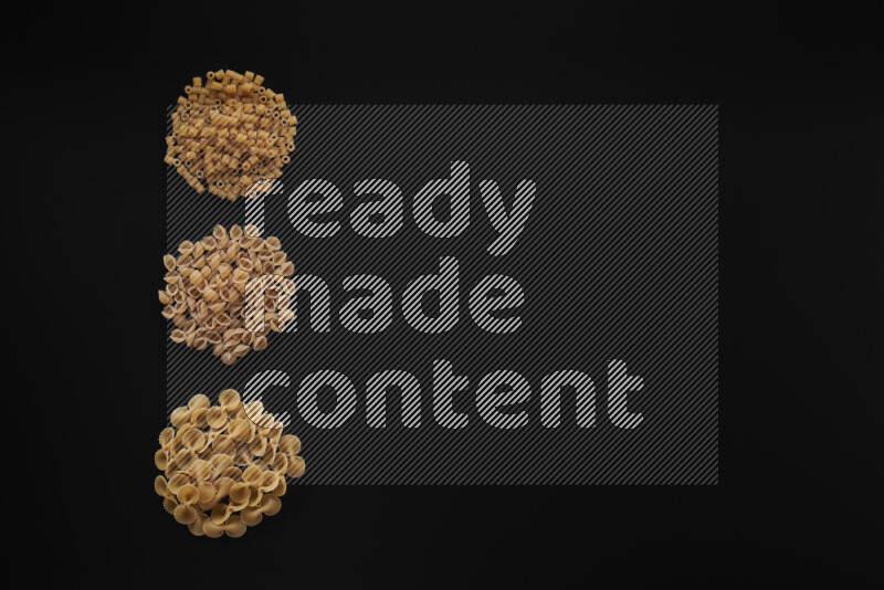 Different pasta types in 3 bunches on black background