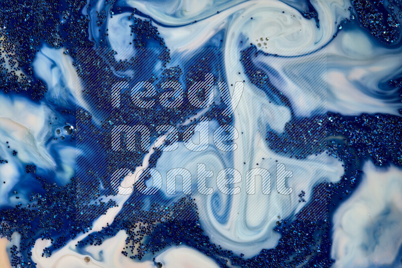 A close-up of sparkling blue glitter scattered on swirling blue and white background