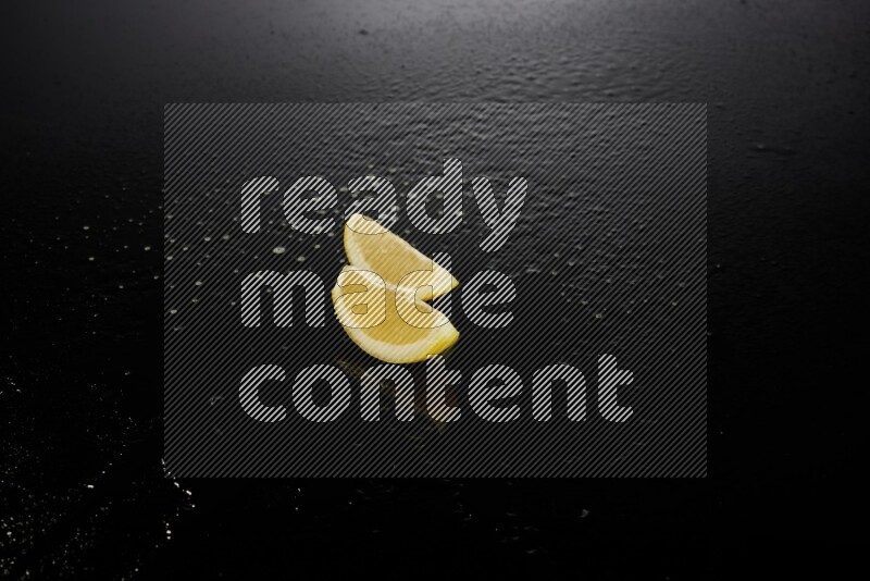 Lemon wedges with water drops, and droplets on black background