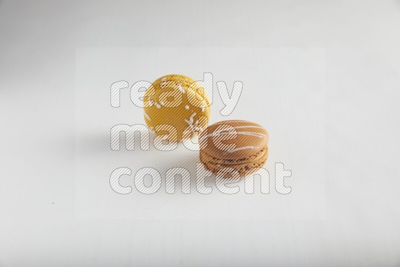 45º Shot of of two assorted Brown Irish Cream, and Yellow Piña Colada macarons on white background