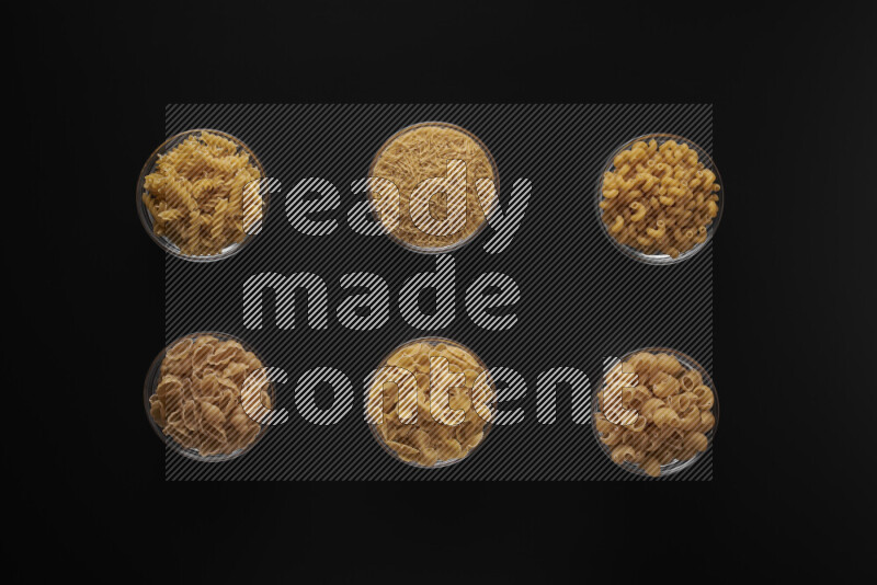 أنواع مختلفة من المعكرونة في أوعية زجاجية علي خلفية سوداء