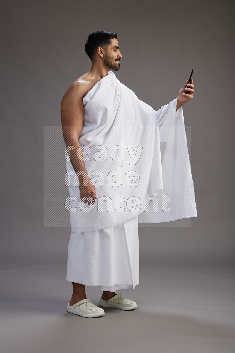 A man wearing Ehram Standing taking selfie on gray background