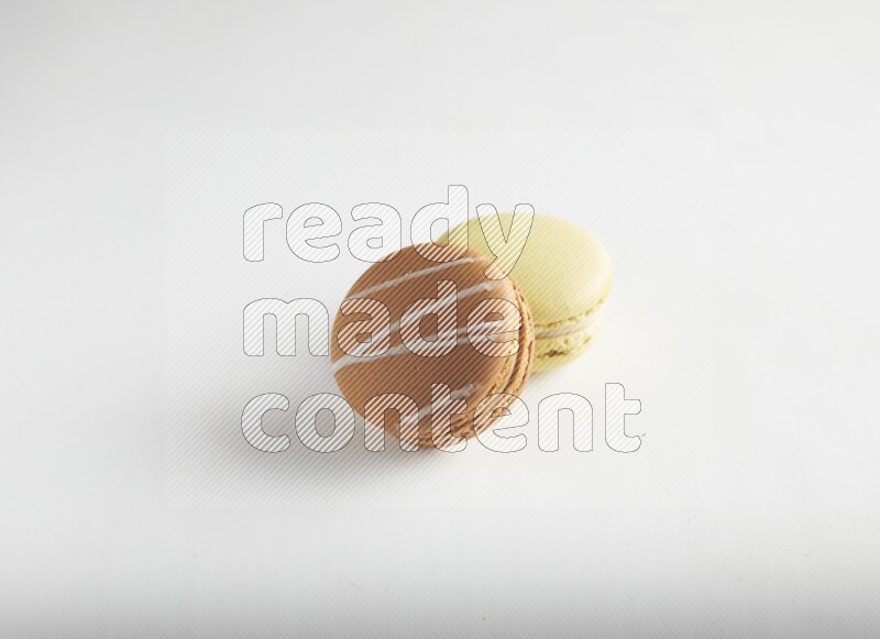 45º Shot of of two assorted Brown Irish Cream, and Yellow Lime macarons on white background