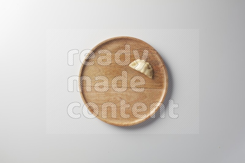 A single Sambosa on a wooden round plate on a white background