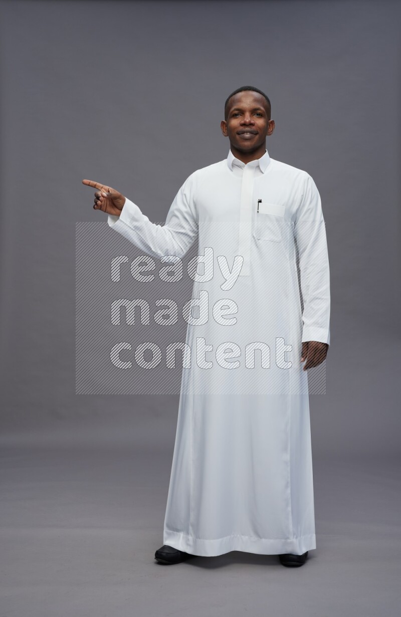 Saudi man wearing thob standing interacting with the camera on gray background