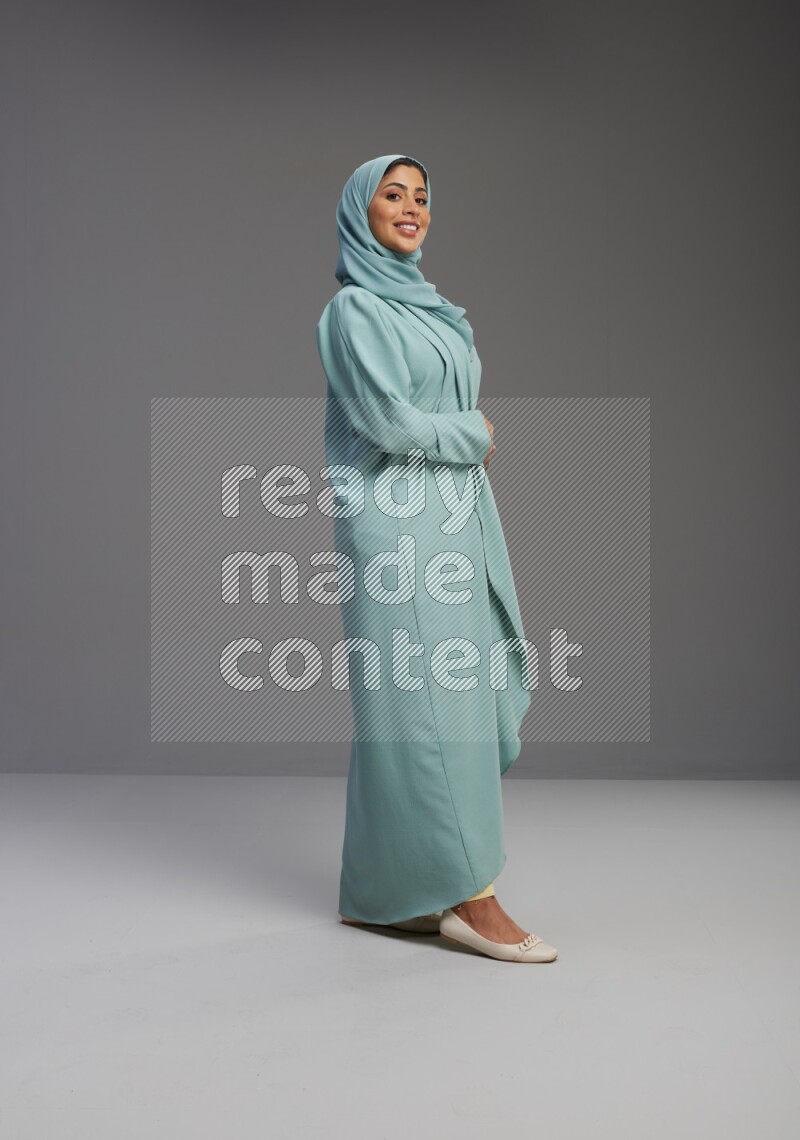 Saudi Woman wearing Abaya standing interacting with the camera on Gray background