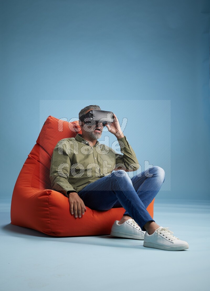 A man sitting on an orange beanbag and gaming with VR