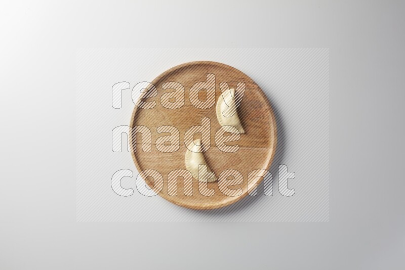 Two Sambosas on a wooden round plate on a white background