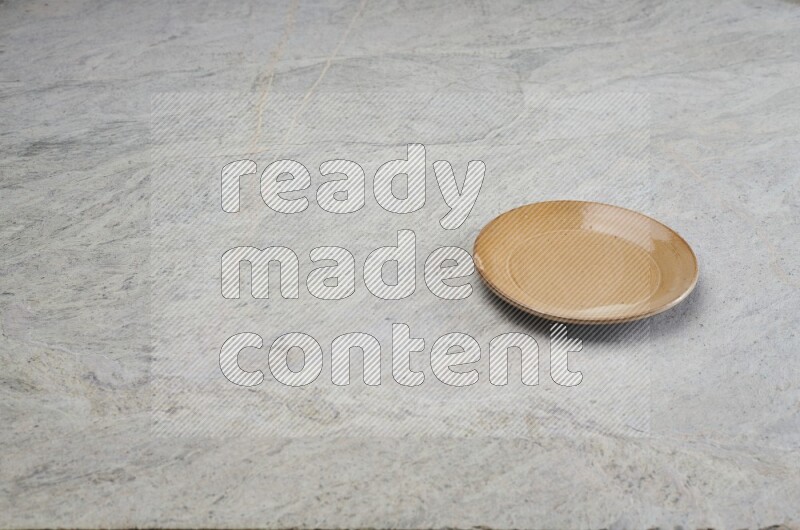 A beige pottery plate on grey marble background