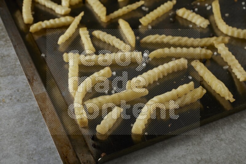 crinkle fries in a black stainless steel rectangle tray on grey textured counter top