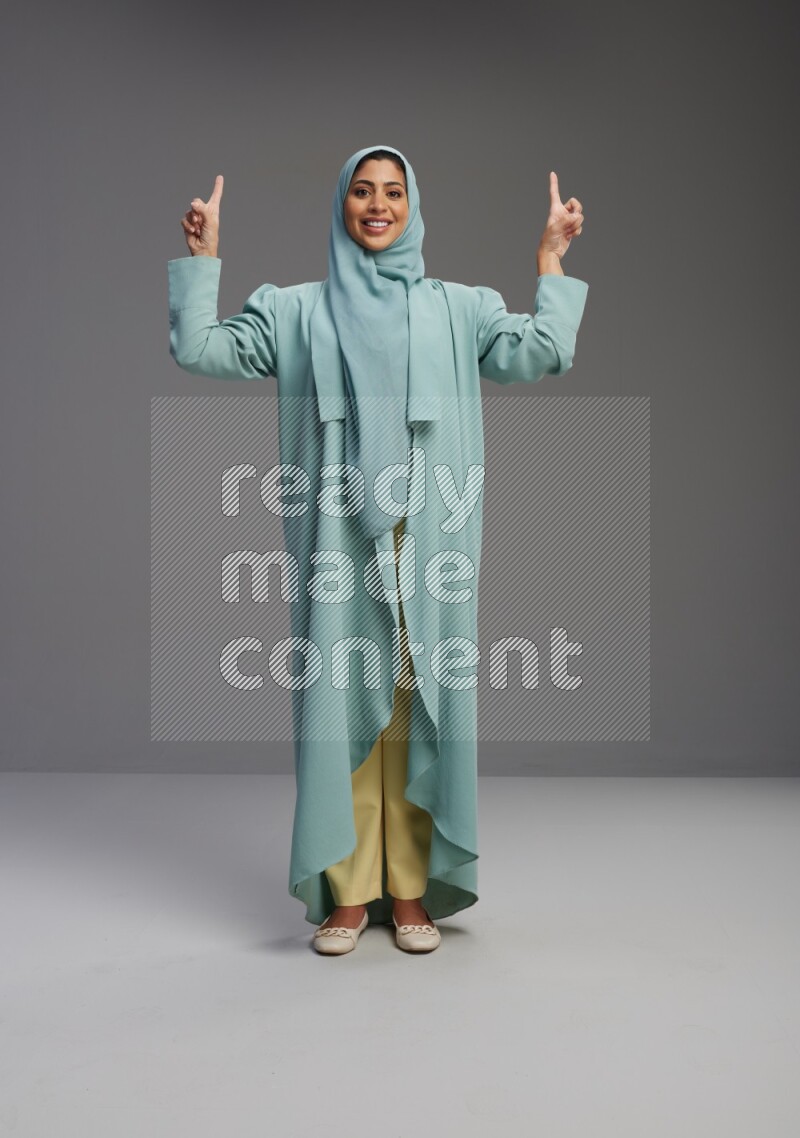 Saudi Woman wearing Abaya standing interacting with the camera on Gray background