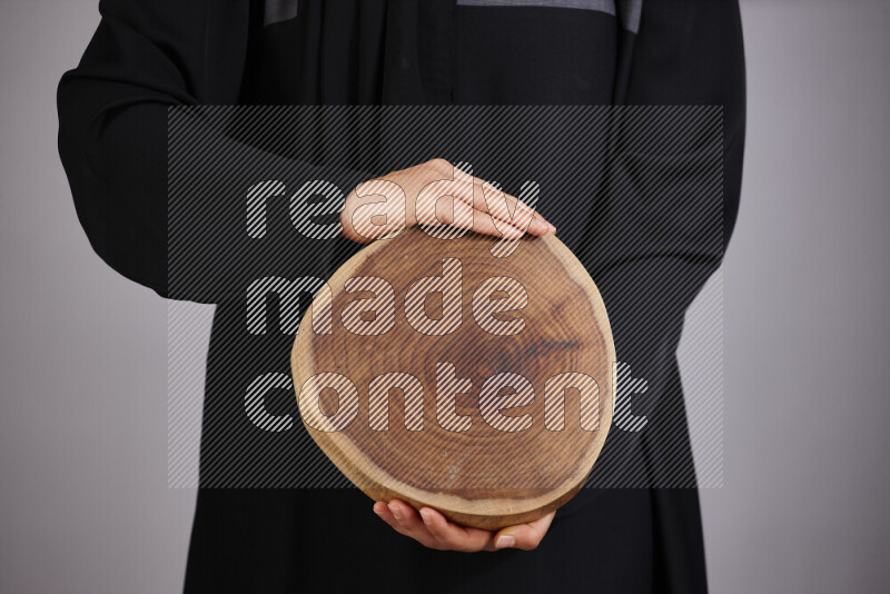 A woman in black abaya holding different wooden essentials in different positions