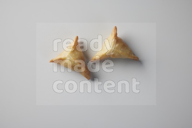 Two fried sambosa from a top angle on a white background