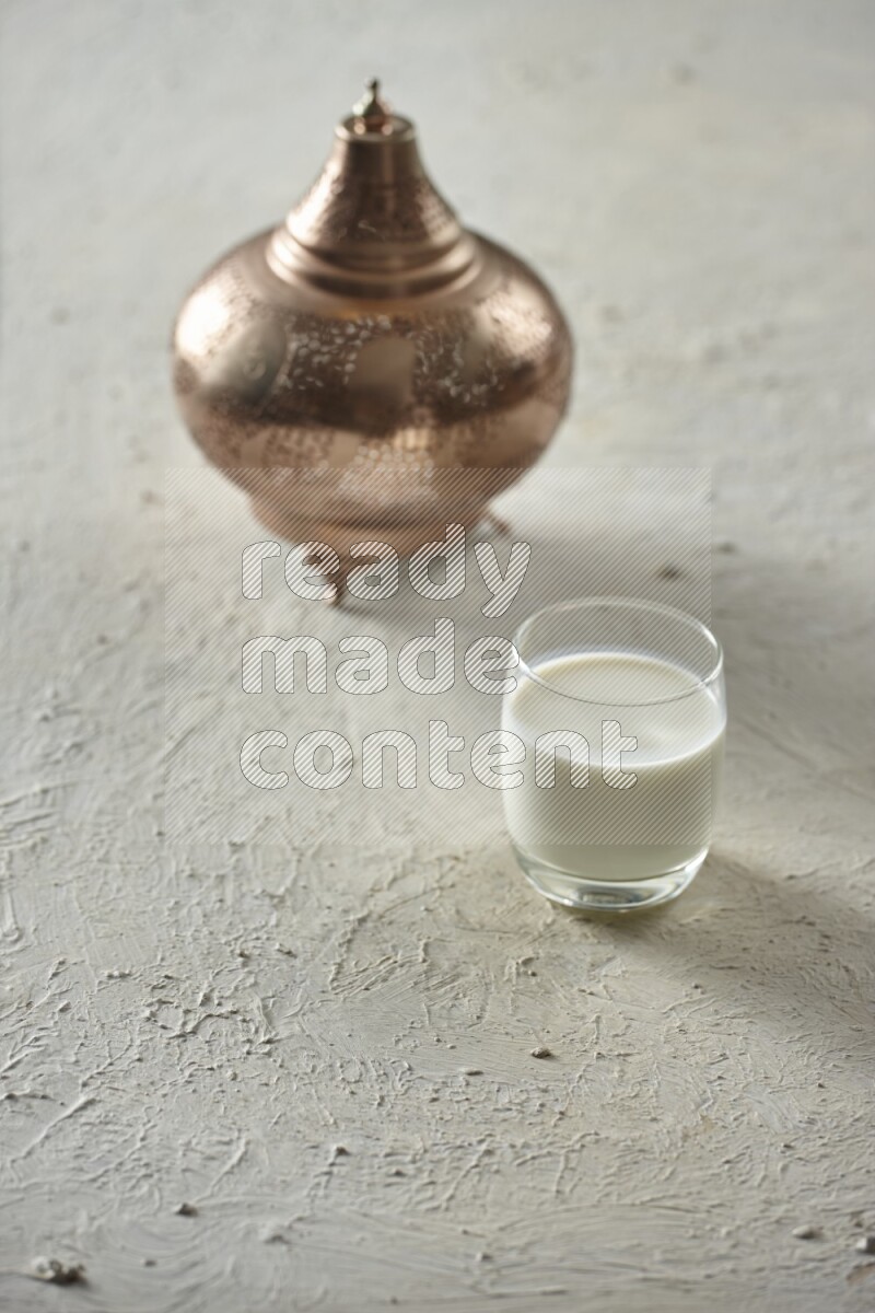 A golden lantern with different drinks, dates, nuts, prayer beads and quran on textured white background