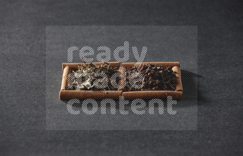 2 squares of cinnamon sticks full of cloves and dried basil on black flooring