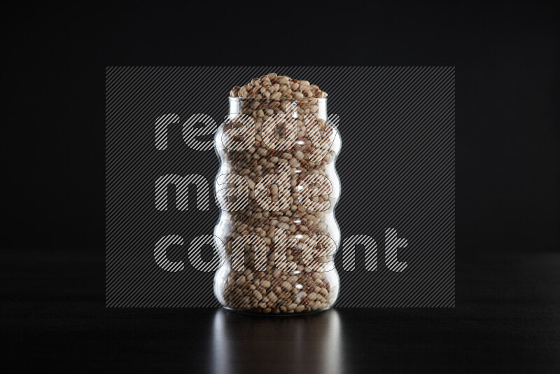 Black-eyed peas in a glass jar on black background