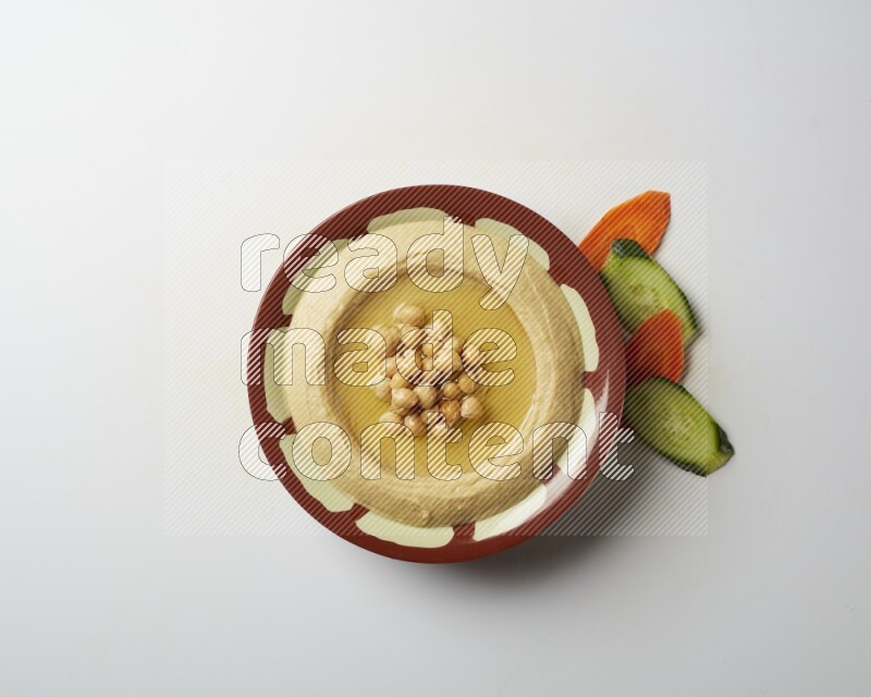 Hummus in a traditional plate garnished with roasted chickpeas  on a white background