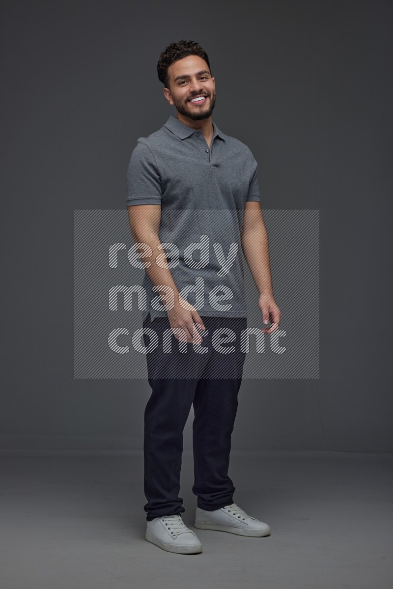 A man wearing casual standing and making multi hand gestures eye level on a gray background