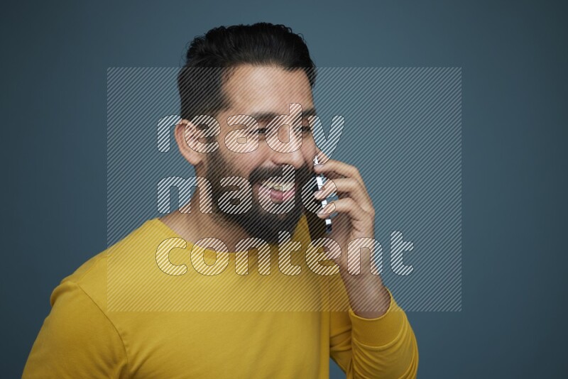 A man having a calling in a blue background wearing a yellow shirt