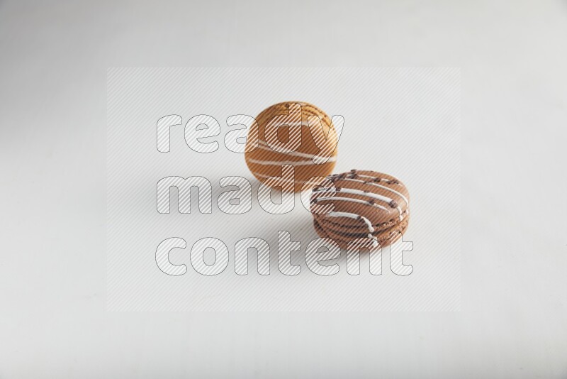 45º Shot of of two assorted Brown Irish Cream, and Brown white Chocolate Caramel macarons on white background