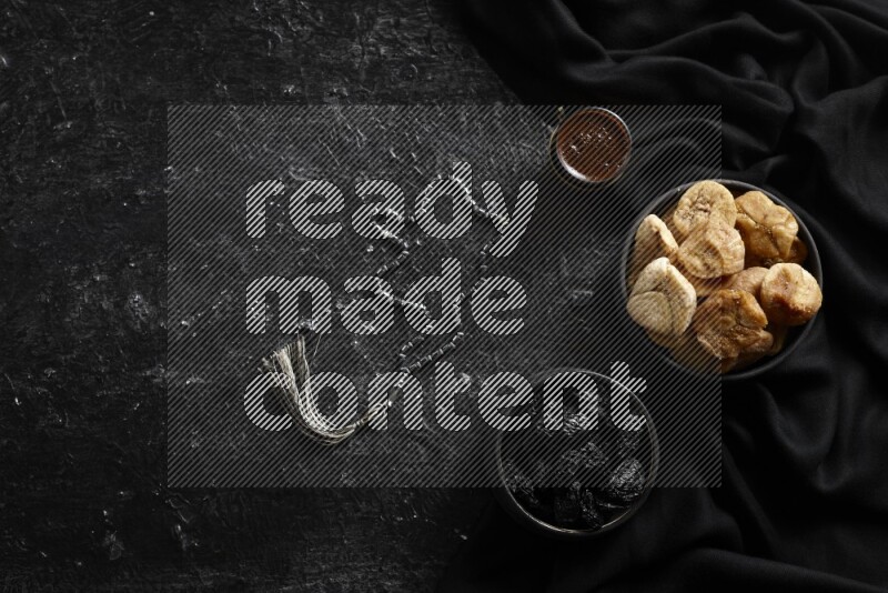 Dried fruits in pottery bowls with coffee in a dark setup