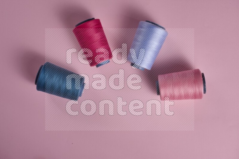 A blue collection of sewing and tailoring tools arranged on a pink background