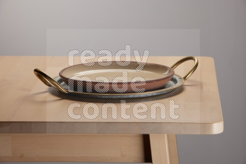 multicolored plate placed on a rounded stainless steel tray with golden handels on the edge of wooden table