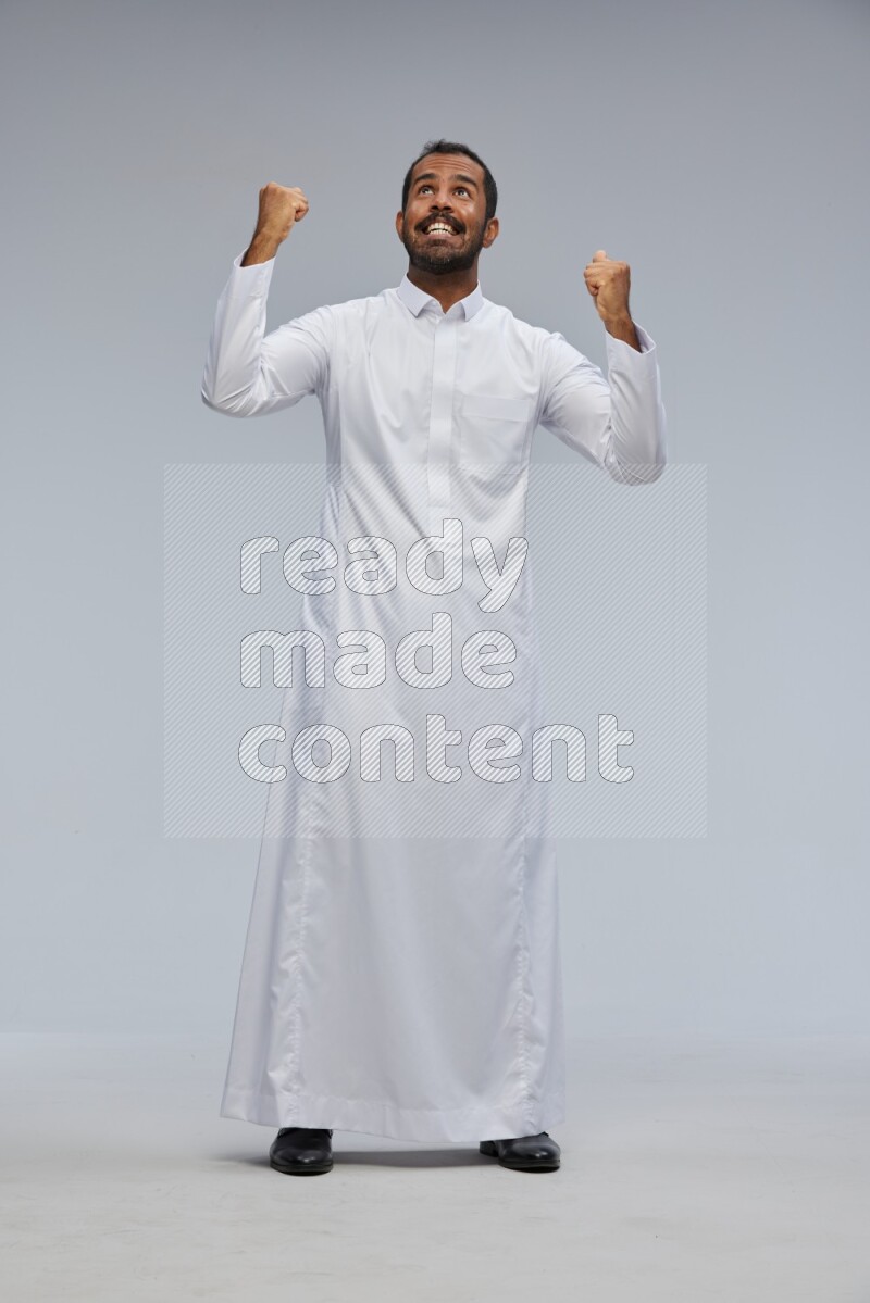 Saudi man Wearing Thob standing interacting with the camera on Gray background