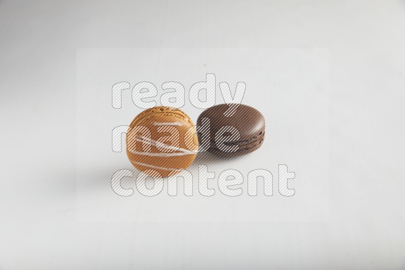 45º Shot of of two assorted Brown Irish Cream, and Brown Dark Chocolate macarons on white background